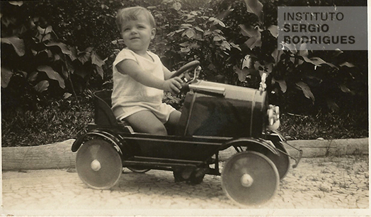 Sergio Rodrigues com aproximadamente 3 anos de idade em seu carrinho, no Rio de Janeiro, por volta de 1930.